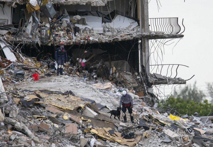 South Florida Urban Search and Rescue team members were among those looking through rubble for signs of survivors at the partially collapsed Champlain Towers South condo building in Surfside, Fla., on Monday. 