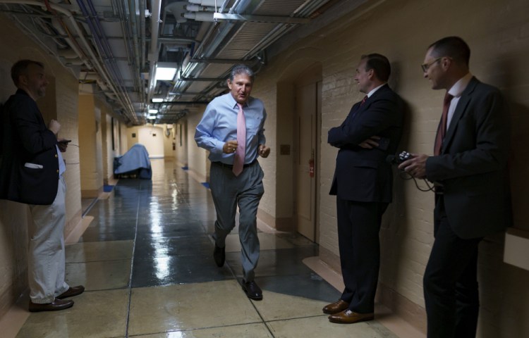 Sen. Joe Manchin, D-W.Va., one of the key Senate infrastructure negotiators, rushes back to a basement room at the Capitol as he and other Democrats work behind closed doors, in Washington on Wednesday. 