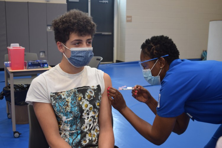 Morse High School sophomore Nick Pesce, 15, holds still while receiving the COVID-19 vaccine Wednesday through a clinic at the school.  