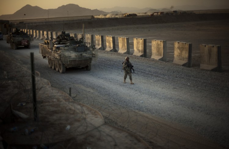 U.S. soldiers from the 5th Striker Brigades walk next to armored vehicles as they arrive at their base Aug. 8, 2009, on the outskirts of Spin Boldak, about 63 miles southeast of Kandahar, Afghanistan.
