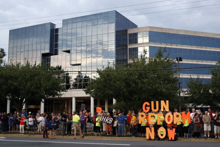 People gather at a vigil for recent victims of gun violence outside the National Rifle Association's headquarters building in Fairfax, Va., in August 2019. While the battle over gun rights is shifting from Washington to the states, the NRA’s message has become so solidified in the Republican political fabric that it’s self-sustaining, even if the gun rights organization that led the way ceases to exist, leaders on both sides say. 