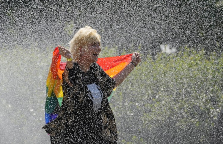 A woman with a rainbow flag cools off in a sprinkler ahead of the Equality Parade, the largest LGBT pride parade in centralcEurope, in Warsaw, Poland, on Saturday.

