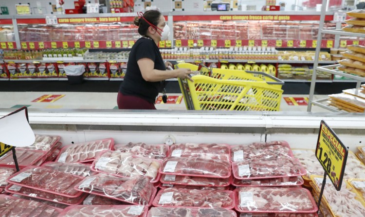 Ashopper wears a mask as she walks through the meat products at a grocery store in Dallas on April 29, 2020.  Wholesale prices, boosted by rising food costs, increased 0.8% in May 2021, and are up by a record amount over the past year.
