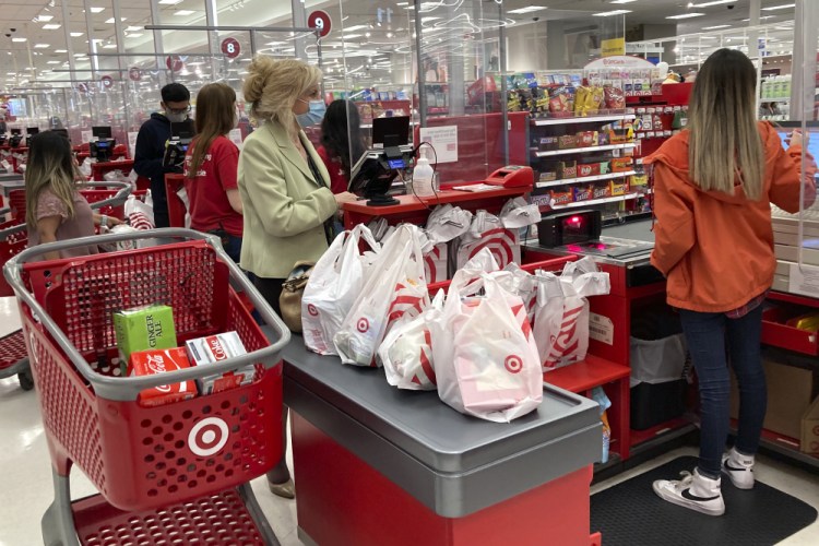 A customer wears a mask as she waits to get a receipt at a register in a Target store in Vernon Hills, Ill., Sunday, May 23. Retail sales fell in May, dragged down by a decline in auto sales, likely due to fewer cars being made amid a pandemic-related shortage of chips. 