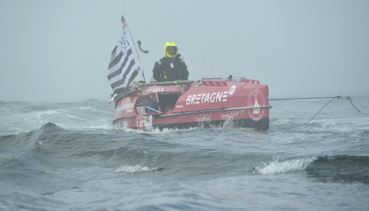 Guirec Soudee is towed through some choppy water to start his journey from Chatham, Mass., to France in his ocean rowboat, Romane on June 15.
