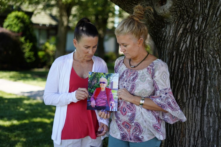 Angela Ermold, right, and her sister, Denise Gracely, hold a photo of their mother, Marian Rauenzahn, on Thursday in Fleetwood, Pa. “They have protected them to death,” Gracely says. 