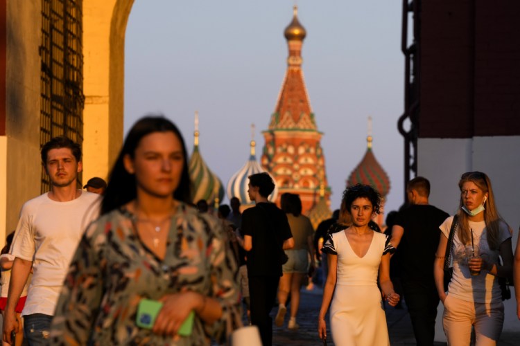 People, most of them without face masks, walk at Red Square during sunset in Moscow on Thursday, June 24.