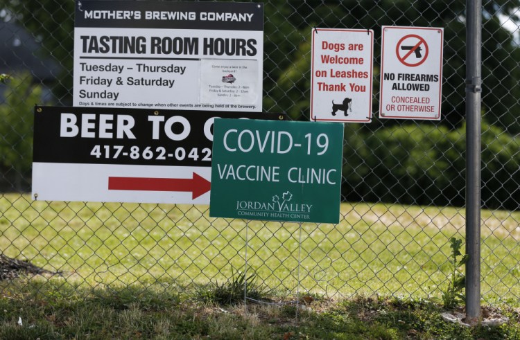Signs hang on a fence for Mother's Brewing Company's COVID-19 vaccine clinic in partnership with the Springfield-Greene County Health Department and Jordan Valley Community Health Center on Tuesday, June 22, 2021, in Springfield, Mo. As the U.S. emerges from the COVID-19 crisis, Missouri is becoming a cautionary tale for the rest of the country: It is seeing an alarming rise in cases because of a combination of the fast-spreading delta variant and stubborn resistance among many people to getting vaccinated. 