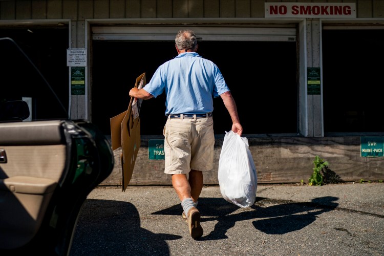 John Maxwell walks cardboard and garbage from his Subaru to a large bin at Eastern Maine Recycling Inc. in Southwest Harbor, Maine. Maxwell and many other residents still sort their recycling out by item, even though the facility stopped recycling all products in recent years. MUST CREDIT: Photo for The Washington Post by Gabe Souza