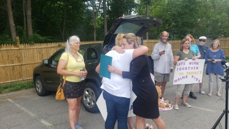 Jessica Gleason, who organized an event July 1 outside the offices of the Maine Department of Health and Human Services in Rockland, hugs the paternal grandmother of Maddox Williams.