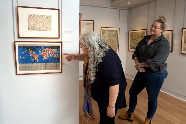 PORTLAND, ME - JULY 19: USM student Morgan Day, left, looks on as Elizabeth Bischof, Professor of History and Executive Director of the Osher Map Library, discusses a piece at the exhibit “Where Will We Go From Here? Travel in the Age of COVID-19”. (Staff photo by Derek Davis/Staff Photographer)