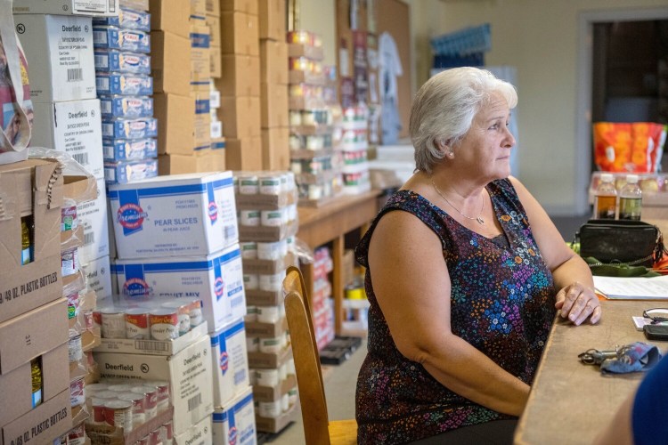 Anne Hodgdon takes a break from stocking the shelves at the food pantry inside St. John's church in Winslow on Wednesday. 