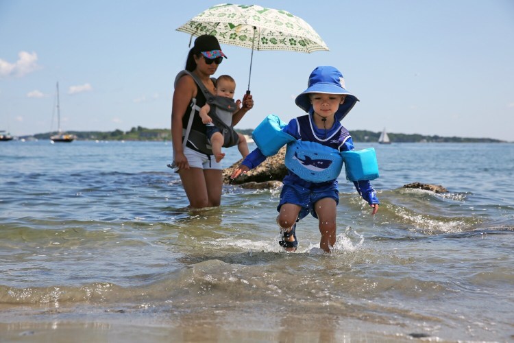 Desmond Predick, 3, emerges from the water with his mother, Jenny Predick, and brother David on Friday at Willard Beach in South Portland.