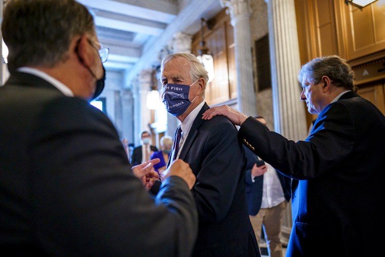 Sen. Angus King of Maine, center, speaks with Sen. Gary Peters, D-Mich., left, while Sen. John Kennedy, R-La., walks by at right, as the Senate votes Friday to formally begin debate on a roughly $1 trillion infrastructure plan.