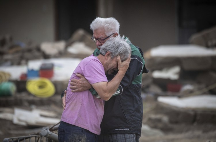 Two brothers weep Monday in front of their parents' house, which was destroyed by the flood in Altenahr, Germany.

