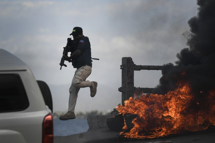 A police officer abandons his vehicle during a demonstration Thursday that turned violent in which protesters demanded justice for the assassinated President Jovenel Moise in Cap-Haitien, Haiti.