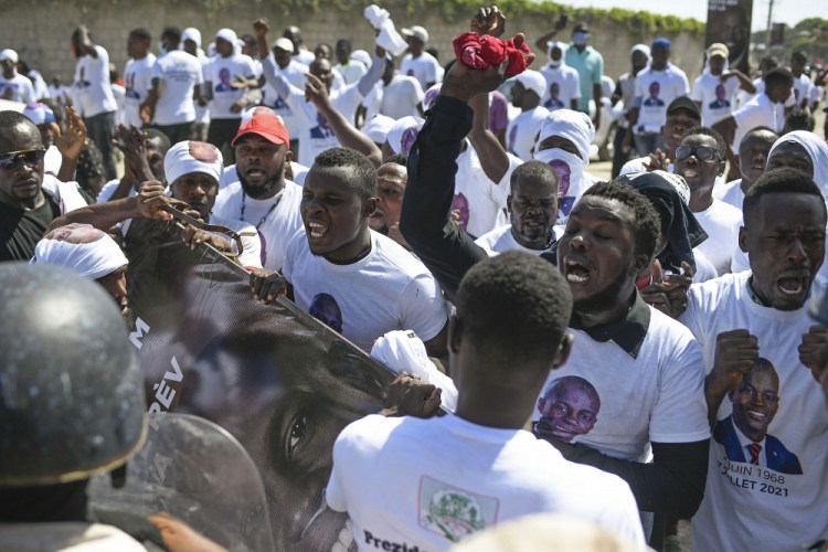 Supporters of slain Haitian President Jovenel Moise are blocked from attending Moise's funeral outside the former leader's family home as they call for justice in Cap-Haitien, Haiti, on Friday. 