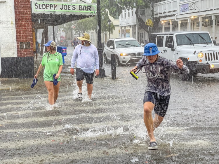 Pedestrians dash across a street as heavy winds and rain  Tropical Storm Elsa passes through Key West, Fla., on Tuesday, July 6, 2021. 