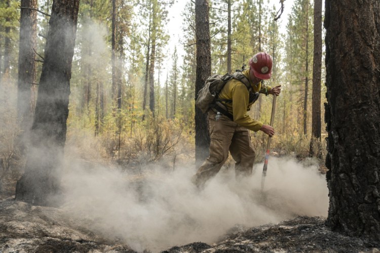 Firefighter Garrett Suza, with the Chiloquin Forest Service, mops up a hot spot on the North East side of the Bootleg Fire on Wednesday near Sprague River, Ore.