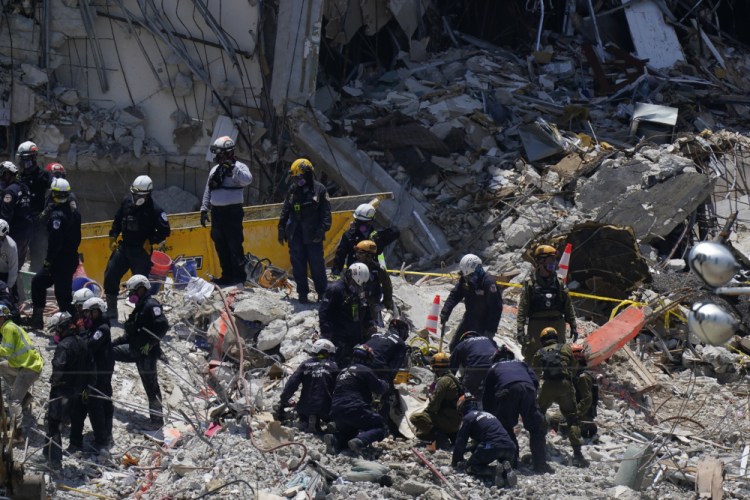 Search and rescue personnel work atop the rubble at the Champlain Towers South condo building, where scores of victims remain missing more than a week after it partially collapsed, on Friday in Surfside, Fla. 