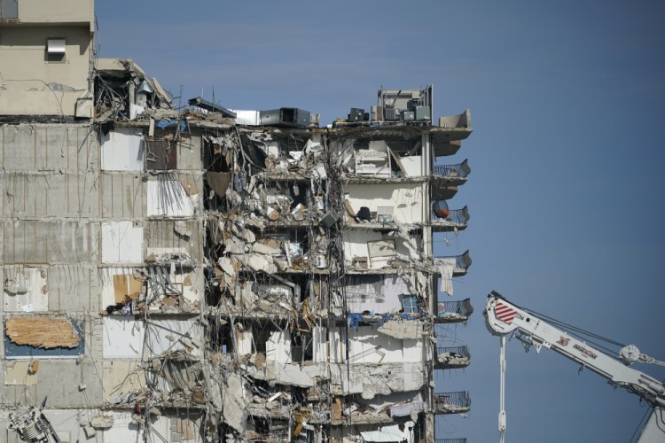 A parked crane sits beside the still standing section of Champlain Towers South, which partially collapsed last Thursday, as rescue efforts on the rubble below were paused out of concern about the stability of the remaining structure, on Thursday in Surfside, Fla.