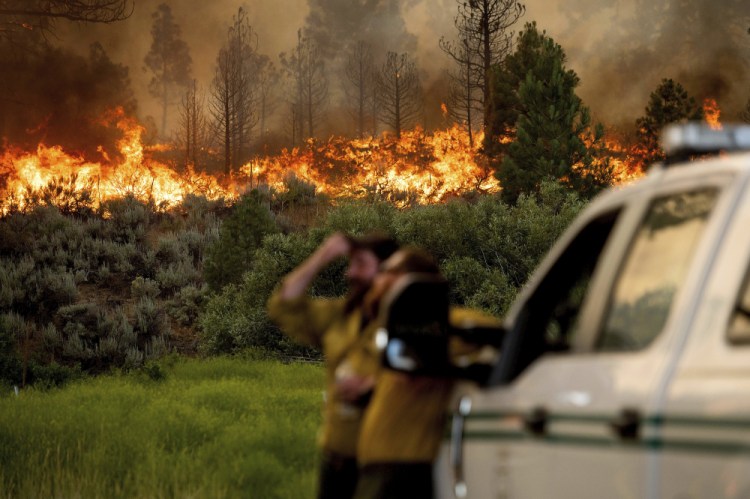 U.S. Forest Service firefighters Chris Voelker, left, and Kyle Jacobson monitor the Sugar Fire, part of the Beckwourth Complex Fire, burning in Plumas National Forest, Calif., on Friday. The Beckwourth Complex – a merging of two lightning-caused fires – headed into Saturday showing no sign of slowing its rush northeast from the Sierra Nevada forest region after doubling in size only a few days earlier. 

