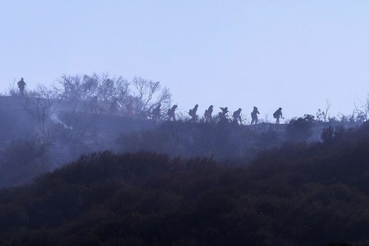 A hotshot hand crew walks in line during a wildfire in Topanga, west of Los Angeles, on Monday. A brush fire scorched about 15 acres in Topanga, initially threatening some structures before fire crews got the upper hand on the blaze. 