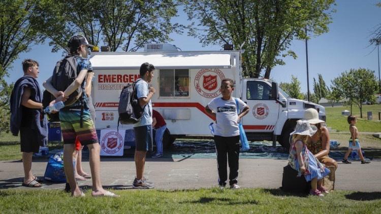 A Salvation Army EMS vehicle is set up as a cooling station as people line up to get into a splash park while trying to beat the heat in Calgary, Alberta, on Wednesday/
