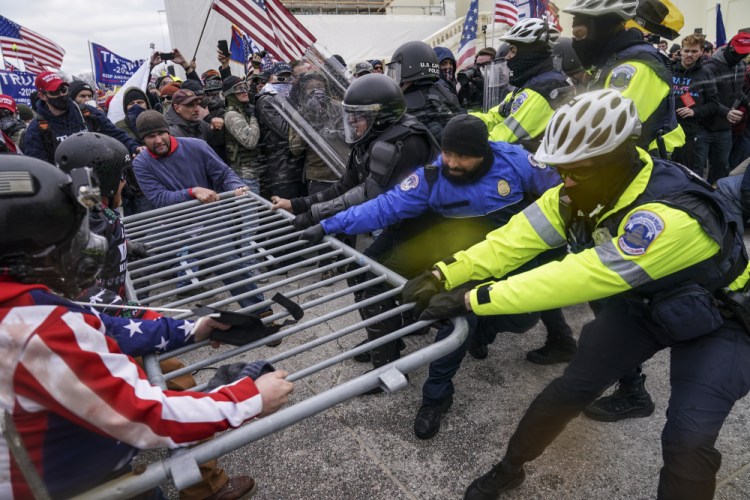 Violent insurrectionists loyal to President Donald Trump hold on to a police barrier at the Capitol in Washington on Jan. 6. Months after Donald Trump’s supporters besieged the Capitol, the ex-president and his supporters are revising their account of that day.