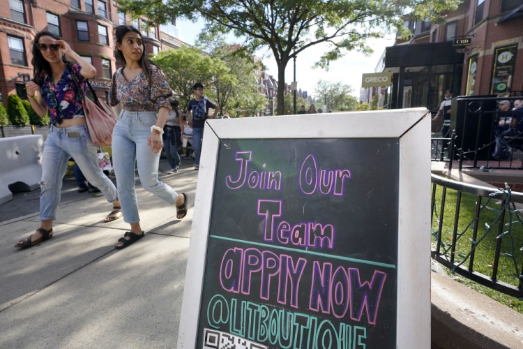 Pedestrians walk past a sign inviting people to apply for employment at a shop in Boston's fashionable Newbury Street neighborhood, on Monday.

