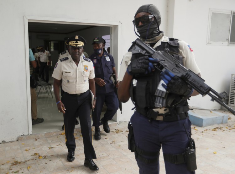 Leon Charles, left, director general of Haiti's police, leaves a room after a news conference at police headquarters in Port-au-Prince on Wednesday. Charles gave an update on the investigation of the  July 7 assassination of President Jovenel Moise.