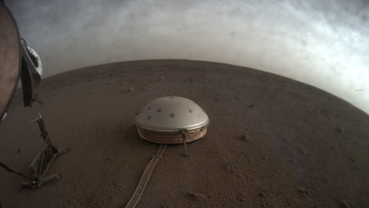 Clouds drift over the dome-covered SEIS seismometer of the InSight lander on the surface of Mars. The quake-measuring device is providing the first detailed look at the red planet’s interior, revealing a surprisingly thin crust and a molten core.