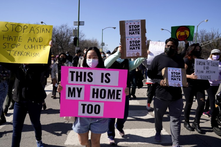 People hold signs as they march during a rally to support Stop Asian Hate at the Logan Square Monument in Chicago in March. 