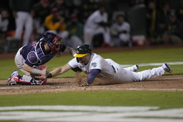 Boston Red Sox catcher Christian Vazquez tags out Oakland Athletics base runner Seth Brown at home plate during the 10th inning Friday night in Oakland, Calif. 