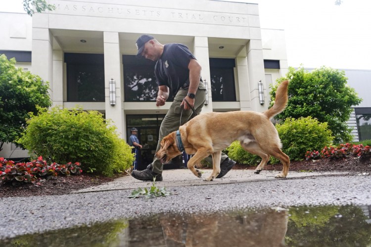 A Massachusetts State Police K-9 team searches for explosives outside Malden District Court, Tuesday, July 6, in Medford, Mass. The men arrested during an armed standoff on Interstate 95 in Massachusetts last weekend appeared in court. 