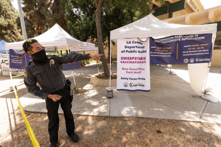 A private security guard gives directions to people looking to get vaccinated, as banners advertise the availability of the Johnson & Johnson and Pfizer COVID-19 vaccines at a county-run vaccination site offering free walk-in vaccinations with no appointment needed at the Eugene A. Obregon Park in Los Angeles on Thursday. 