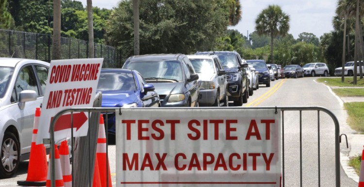 Signage stands at the ready in case COVID-19 testing at Barnett Park reaches capacity, as cars wait in line in Orlando, Fla., on Thursday.



