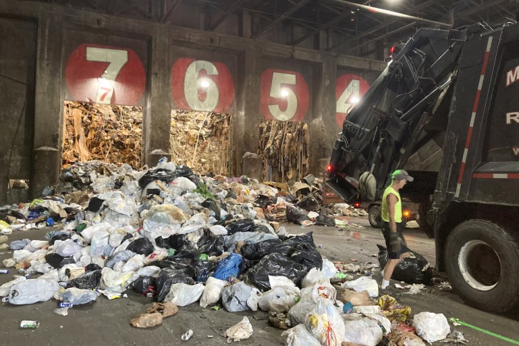 A worker unloads a garbage truck at ecomaine in Portland in June.