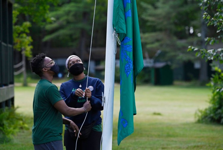 OTISFIELD, ME - JULY 29: Counselors Boniface Kabongo, left and his sister Marie-Monique Kabongo of South Portland raise the Seeds of Peace flag during opening ceremonies at Seeds of Peace in Otisfield Monday, August 2, 2021. (Staff Photo by Shawn Patrick Ouellette/Staff Photographer)