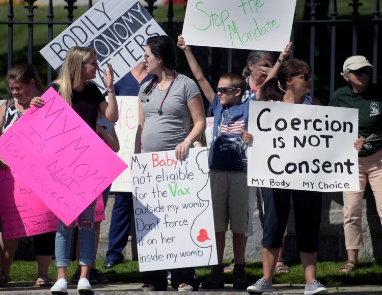 People protest Monday outside the State House. The crowd objected to a vaccine mandate issued by the state last week requiring health care workers to be inoculated against COVID-19.