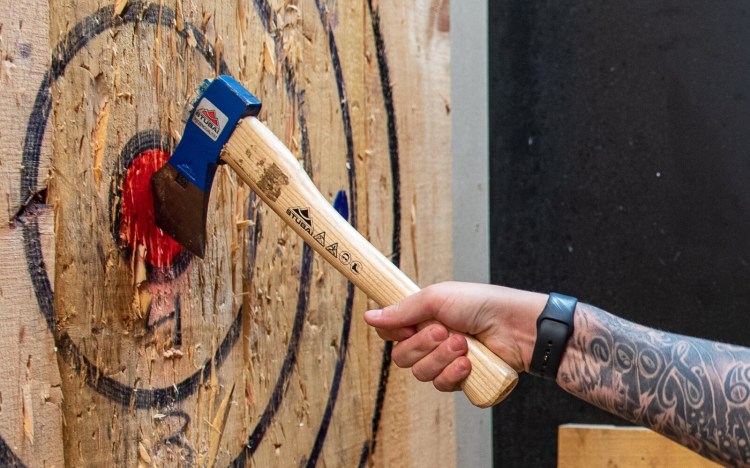 Christina Tucci pulls her axe from the bullseye that she just hit with one of her throws Thursday night at Splittin' Wood Axe Throwing at the Lewiston Mall.