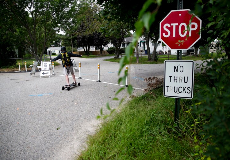 SOUTH PORTLAND, ME - AUGUST 21: A boy skateboards past temporary signs directing traffic away from a residential neighborhood in the Cash Corner neighborhood in South Portland. The City of South Portland and the Greater Portland Council of Governments installed several traffic calming treatments in order to analyze existing conditions and develop a report on traffic calming implementations. These installations will be in place for a trial period of two months, with removal anticipated for early October. (Davis/Staff Photographer)