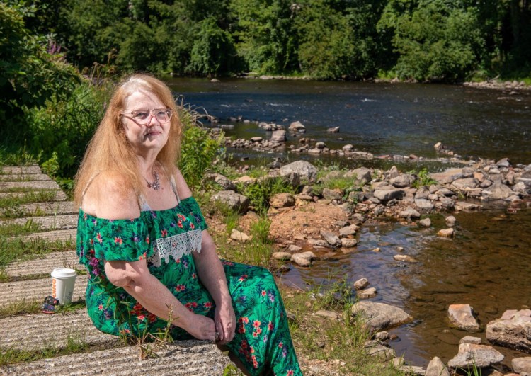 Jodi Floyd sits Tuesday on the banks of the Androscoggin River in Auburn, where her husband Marvin once enjoyed fishing. Floyd believes staff at Russell Park Rehabilitation and Living Center brought COVID-19 into the facility where Marvin was living. He died after being infected with the virus last year.