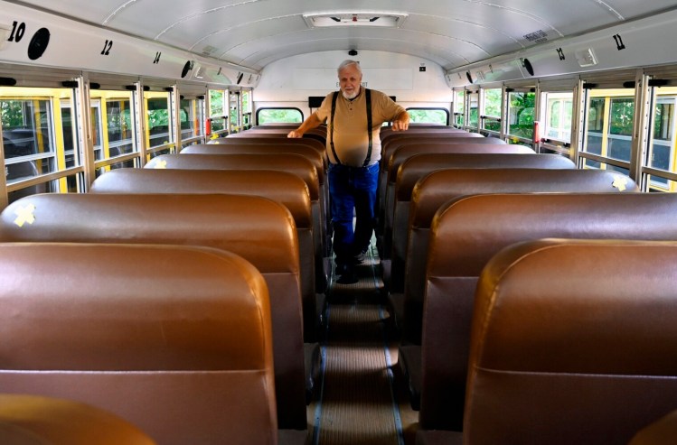 School bus driver Tom Hudak makes his pre-trip inspection at the SAD 15 bus garage before driving a sports team to a scrimmage Wednesday. Hudak retired from driving buses with another school district but was encouraged to start driving again a few years ago to help out with the shortage of drivers. 