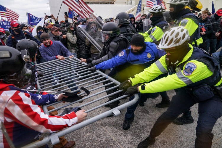 Violent insurrectionists loyal to President Donald Trump hold on to a police barrier at the Capitol in Washington on Jan. 6.  