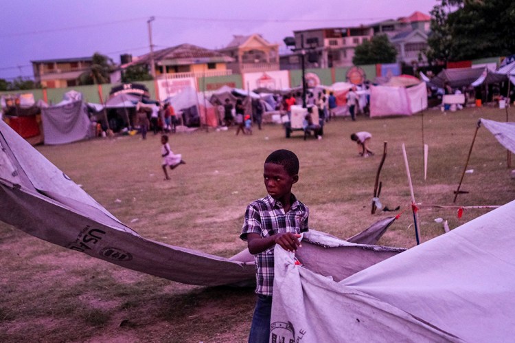 A boy stands at a makeshift camp for people whose homes collapsed during the earthquake, at a soccer field, at sunset in Les Cayes, Haiti, Monday, Aug. 16, 2021, two days after a 7.2-magnitude earthquake struck the southwestern part of the country. (AP Photo/Matias Delacroix)