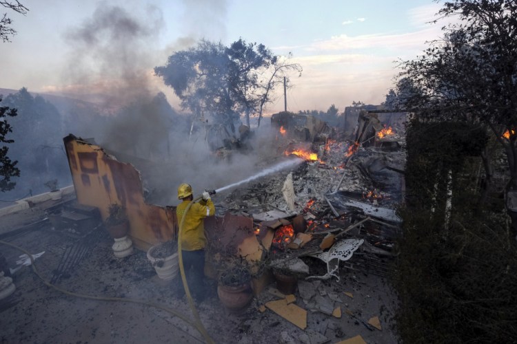 A firefighter tries to extinguish the flames at a burning house as the South Fire burns in Lytle Creek, San Bernardino County, north of Rialto, Calif., on Wednesday. 