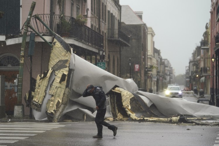A man passes by a section of roof that was blown off of a building in the French Quarter by Hurricane Ida winds, Sunday in New Orleans.