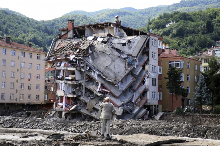 A man looks at a building that collapsed because of flooding and landslides in Bozkurt, Turkey, on Saturday. (AP Photo)