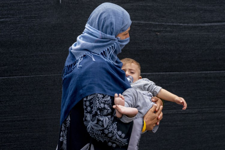A woman evacuated from Afghanistan steps off a bus with a baby as they arrive at a processing center in Chantilly, Virginia, on Monday after arriving on a flight at Dulles International Airport. 